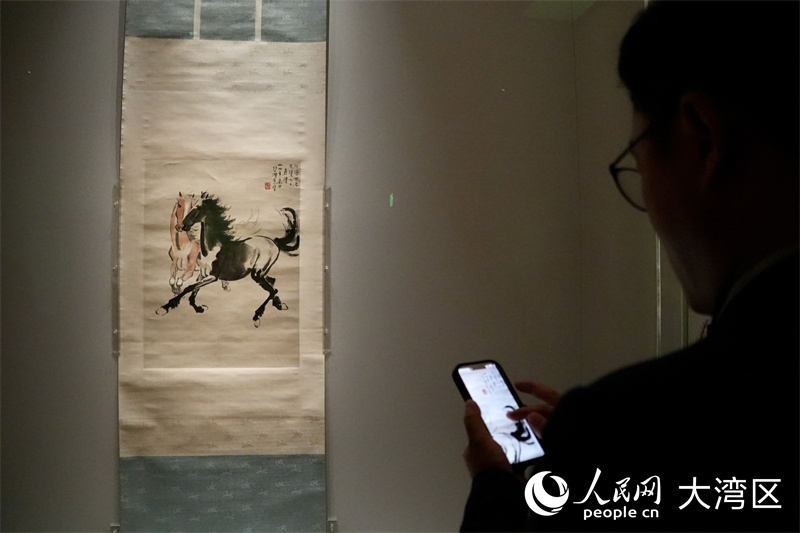图1. 19日传媒预览现场，记者在拍摄徐悲鸿的《双马图》。人民网严小晶 摄